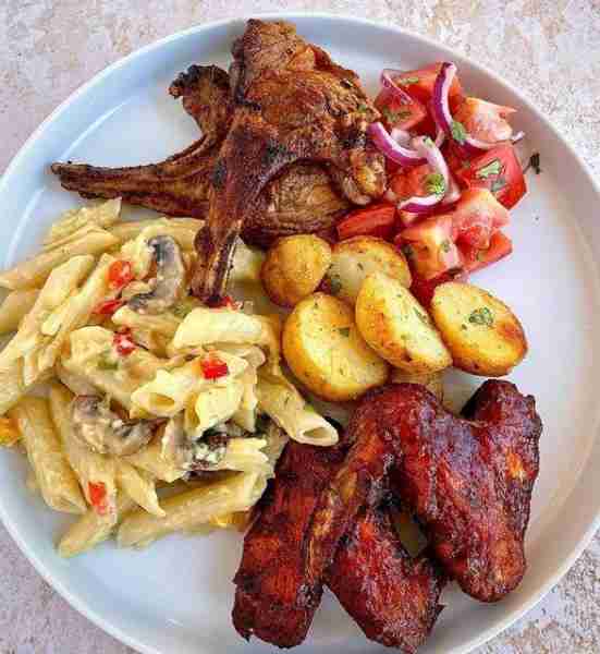 A Delectable Plate of Grilled Lamb Chops, Barbecue Wings, Creamy Pasta, and Roasted Potatoes Must ex...