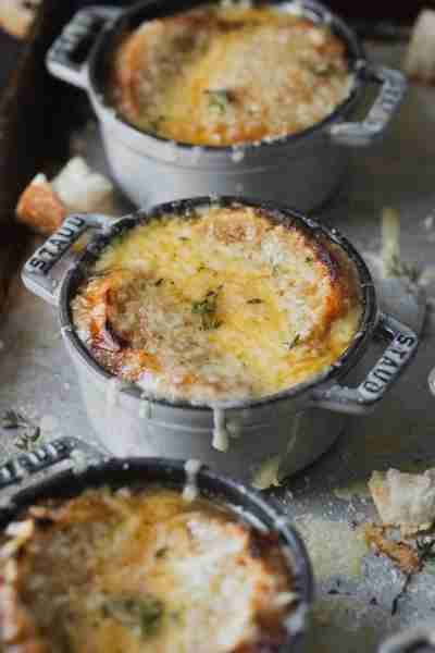 Perfectly caramelized onions in a savory broth are topped with a crusty piece of bread lathered in m...
