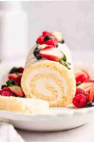 Soft vanilla cake roll filled with tangy cream cheese frosting, dusted with powdered sugar, and perf...