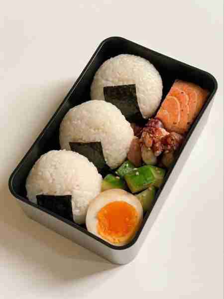 Japanese Bento Box with Onigiri, Grilled Salmon, Soft-Boiled Egg, and Pickled Vegetables Ingredients...