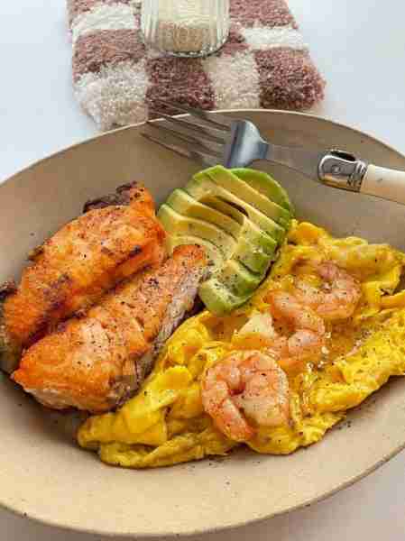 A protein-packed meal with grilled salmon 🐟, creamy scrambled eggs 🍳 topped with shrimp 🍤, and fr...