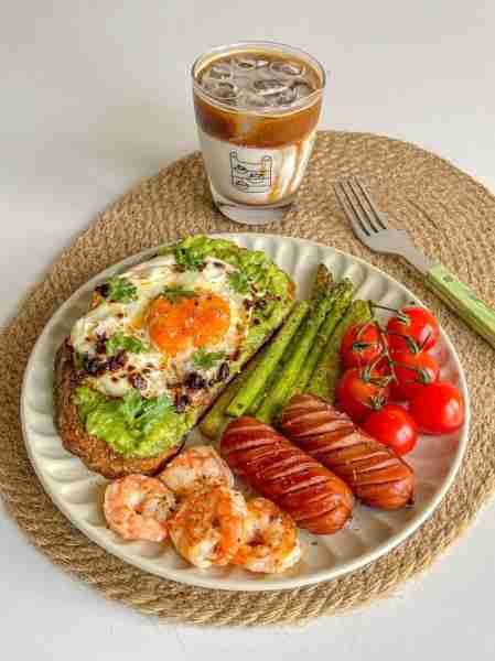 A colorful breakfast plate 🍳🥑 — creamy avocado toast topped with a sunny-side egg, juicy shrimp 🍤...