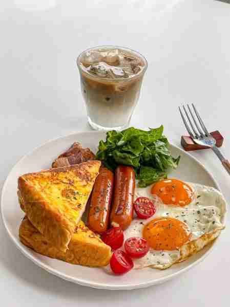 “Golden mornings start like this 🍳☕ Sunny eggs, crispy toast, and a cold latte — pure breakfast bl...