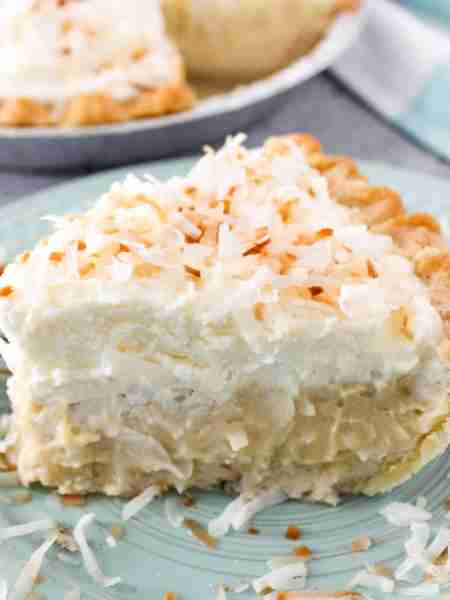 Silky coconut cream custard pie piled high with fresh whipped cream and toasted coconut! 🩷
